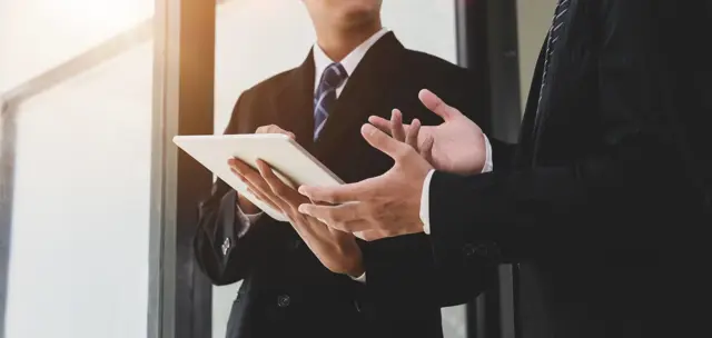 Businesspeople discussing information displayed on a tablet Businesspeople discussing information displayed on a tablet