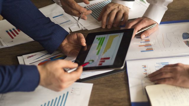 Three people reviewing a financial chart 