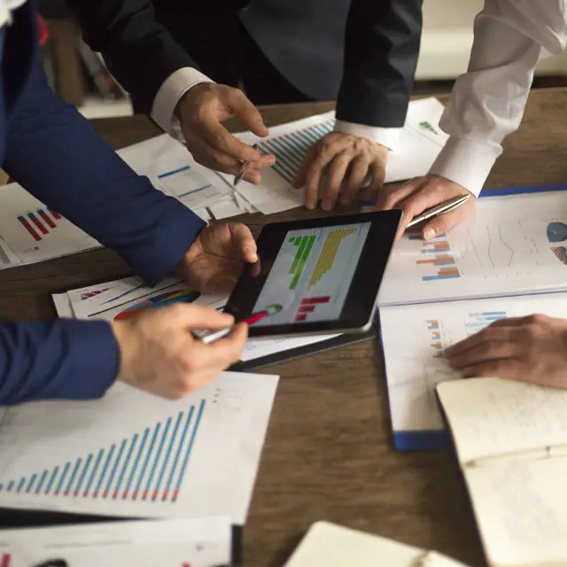 Three people reviewing a financial chart Three people reviewing a financial chart